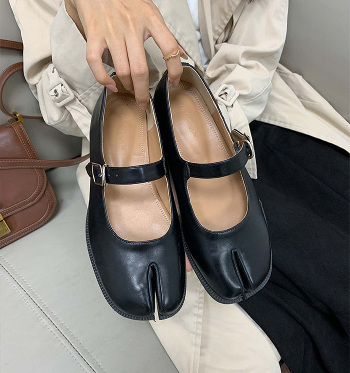 Chaussures Mary Jane noires à bout fendu "tabi" dans les mains d'une femme. Détails : bride à boucle, sac marron. Mode unique., 45286632947893,45286632980661,45286633013429,45286633046197,45286633078965,45286633111733,45286633144501,45286633177269,45286633210037,45286633242805,45286633275573,45286633308341,45286633341109,45286633373877,45286633406645,45286633439413,45286633472181,45286633504949,45286633537717,45286633570485,45286633603253,45286633636021,45286633668789,45286633701557