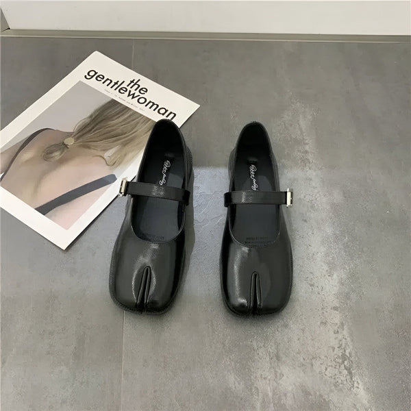 Image de deux chaussures Mary Jane noires à bout fendu, posées à côté d'un magazine intitulé "The Gentlewoman" sur un sol gris. Chaussures en cuir verni avec une bride et une boucle., 45286636585141,45286636617909,45286636650677,45286636683445,45286636716213,45286636748981