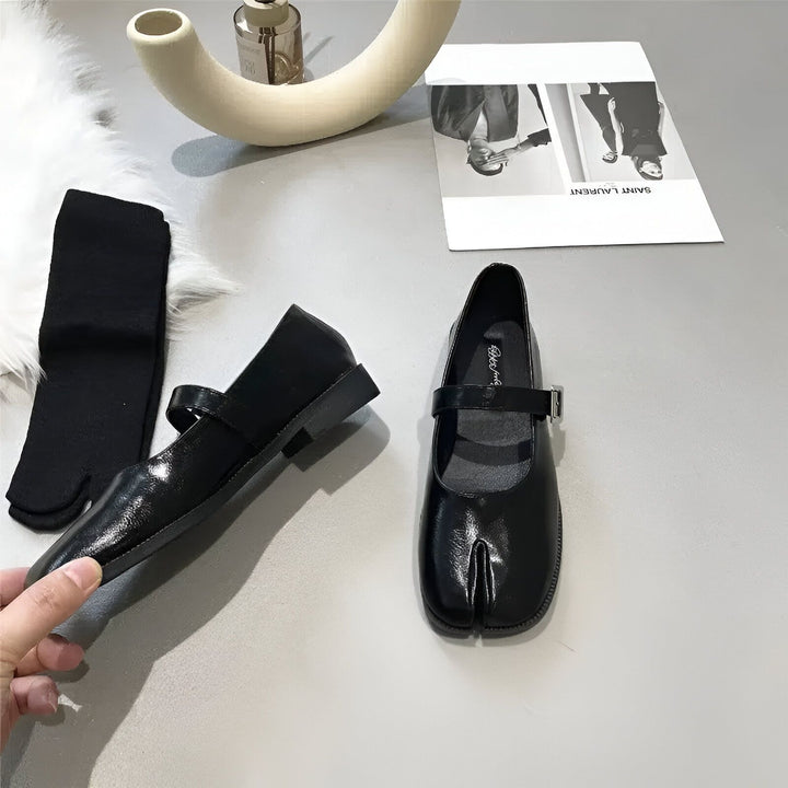 Image de nature morte présentant une paire de chaussures Mary Janes noires à bout fendu, portées avec des chaussettes noires tabi, un vase décoratif et un imprimé de Saint Laurent., 45286636585141,45286636617909,45286636650677,45286636683445,45286636716213,45286636748981