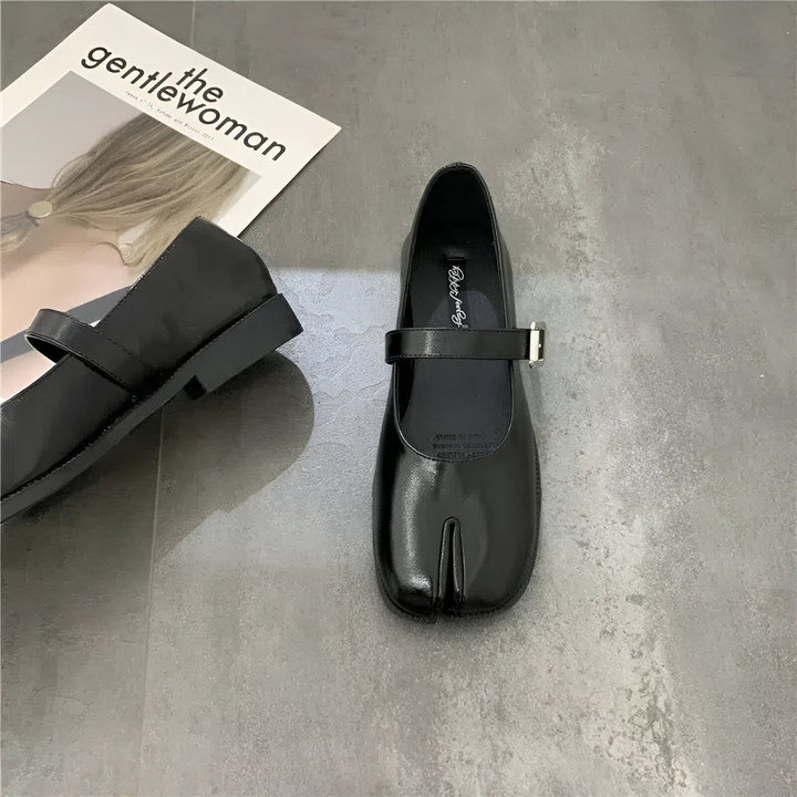 Vue rapprochée de chaussures Mary Jane noires à bout fendu avec une lanière à boucle, posées sur un sol gris avec un magazine "the gentlewoman" en arrière-plan., 45286636585141,45286636617909,45286636650677,45286636683445,45286636716213,45286636748981