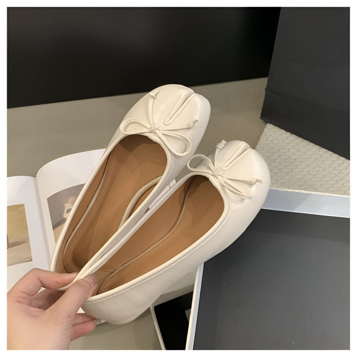Image rapprochée de deux ballerines blanches en cuir, avec un nœud décoratif. L'intérieur est brun clair. Elles sont posées sur un magazine et une boîte noire. Chaussures plates pour femmes., 45286631932085,45286631964853,45286631997621,45286632030389,45286632063157,45286632095925,45286632128693,45286632161461,45286632194229,45286632226997,45286632259765,45286632292533,45286632325301,45286632358069,45286632390837,45286632423605,45286632456373,45286632489141,45286632521909,45286632554677,452866325874