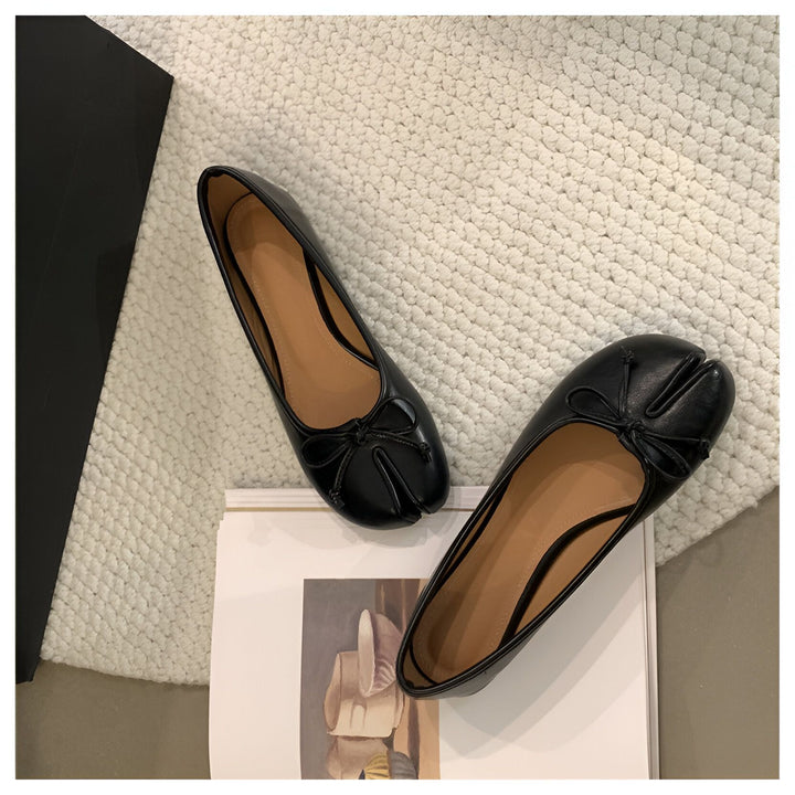 Image de deux ballerines noires en cuir avec un design tabi à l'avant, ornées de petits nœuds. Elles sont posées sur un tapis clair et un livre. Chaussures élégantes et modernes., 45286631932085,45286631964853,45286631997621,45286632030389,45286632063157,45286632095925,45286632128693,45286632161461,45286632194229,45286632226997,45286632259765,45286632292533,45286632325301,45286632358069,45286632390837,45286632423605,45286632456373,45286632489141,45286632521909,45286632554677,45286632587445,452866326