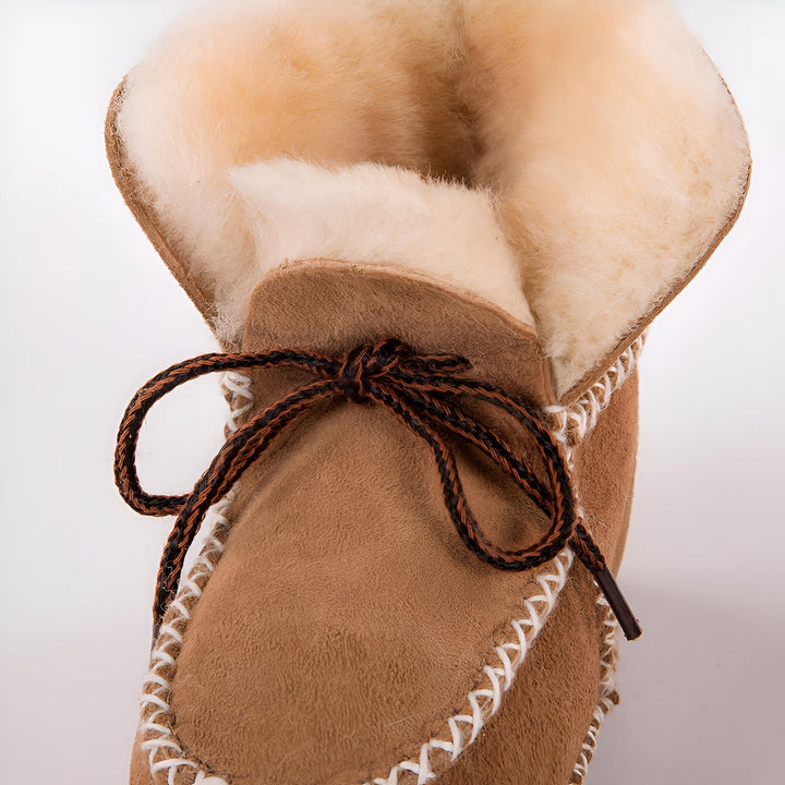 Chaussons mocassins en peau de mouton couleur caramel. Fourrure intérieure crème pour la chaleur. Lacets noués marron et noir sur le dessus. Couture blanche décorative visible. Idéal pour le confort à la maison., 45286950502581,45286950535349,45286950568117,45286950600885,45286950633653,45286950666421,45286950699189,45286950731957,45286950764725