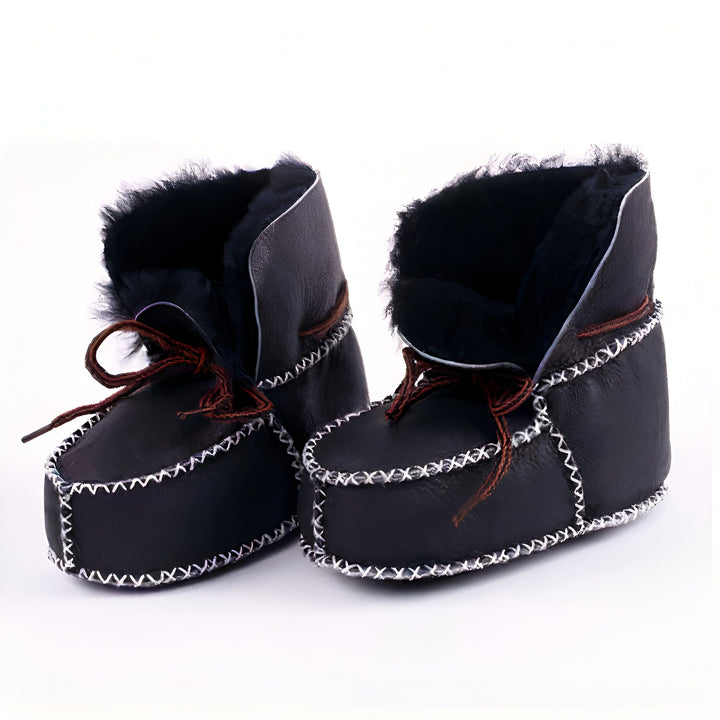 Paire de chaussons pour bébé en cuir noir avec des coutures blanches décoratives. L'intérieur est en fourrure noire douce et ils sont lacés avec des cordons marron. Chaussures confortables et chaudes pour les petits pieds., 45286950502581,45286950535349,45286950568117,45286950600885,45286950633653,45286950666421,45286950699189,45286950731957,45286950764725