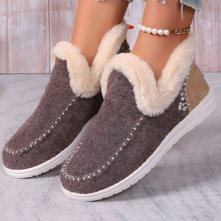 Gros plan sur des chaussons mules d'intérieur marron avec bordure en fausse fourrure crème, portés avec une chaîne de cheville à perles. Confortables et chauds, idéals pour la maison., 45286658375861