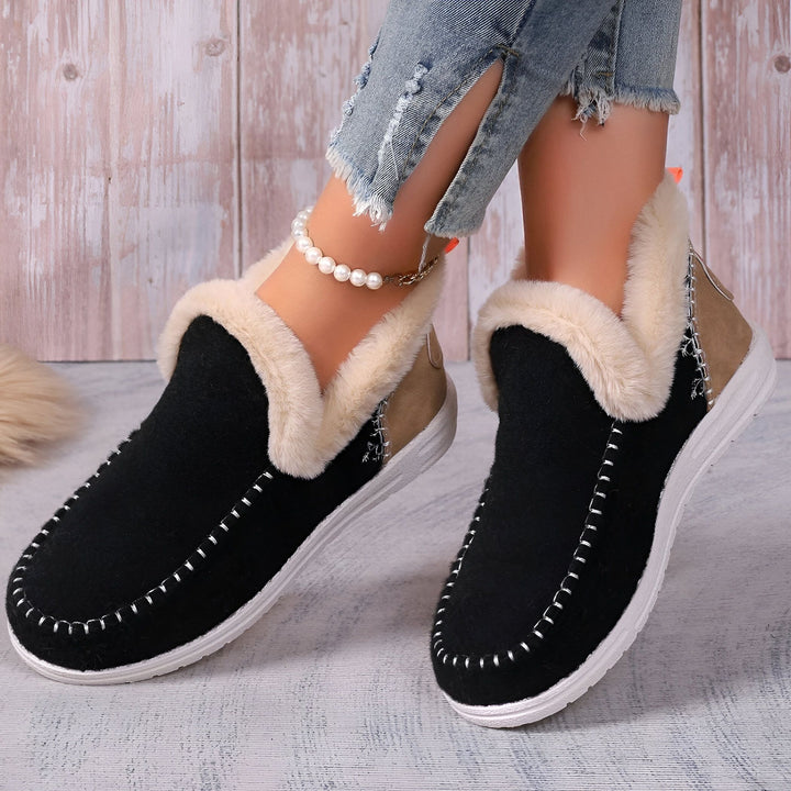 Gros plan de chaussons d'intérieur noirs et beiges, bordés de fausse fourrure, portés avec un jean déchiré et une chaîne de cheville à perles. Idéal pour un confort chaleureux à la maison., 45286658375861