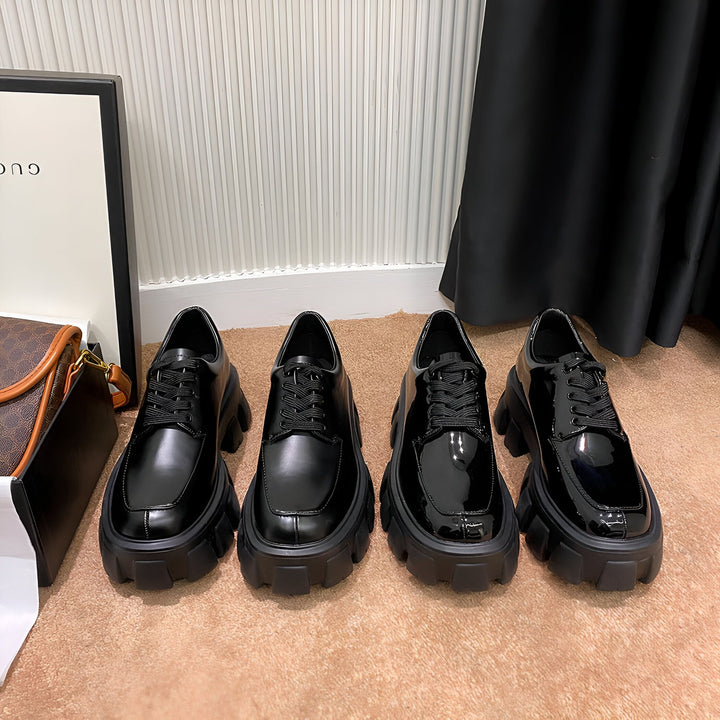 Quatre paires de chaussures derby noires vernies à lacets, avec semelles épaisses crantées, posées sur un tapis marron clair. Sac à main et cadre Gucci en arrière-plan., 45286884180149,45286884212917,45286884245685,45286884278453,45286884311221,45286884343989,45286884376757,45286884409525,45286884442293,45286884475061