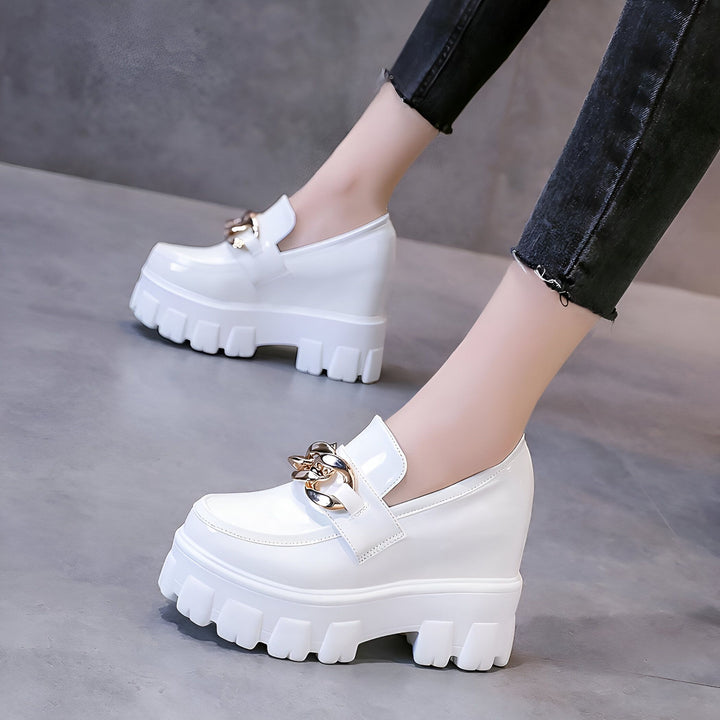 Gros plan sur des chaussures compensées blanches vernies avec une chaîne dorée, portées avec un jean noir. Chaussures de mode pour femmes, style audacieux et tendance., 45286934839477,45286934872245,45286934905013,45286934937781,45286934970549,45286935003317,45286935036085,45286935068853,45286935101621,45286935134389,45286935167157,45286935199925