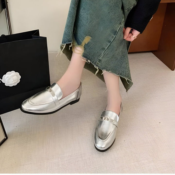 Mocassins argentés élégants portés avec une jupe en jean délavé. Sac à provisions noir en arrière-plan. Chaussures tendance pour femme, parfaites pour un look décontracté chic., 45286708412597,45286708445365,45286708478133,45286708510901,45286708543669