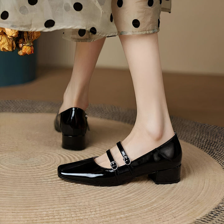 Gros plan sur une femme portant des chaussures Mary Janes vernies noires à talons carrés. La robe à pois ajoute une touche rétro., 45286703071413,45286703104181,45286703136949,45286703169717,45286703202485,45286703235253,45286703268021,45286703300789,45286703333557,45286703366325,45286703399093,45286703431861