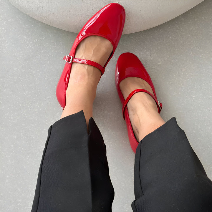 Vue plongeante des pieds d'une personne portant des ballerines rouges vernies avec une bride. Elle porte un pantalon noir., 45286700941493,45286700974261,45286701007029,45286701039797,45286701072565,45286701105333,45286701138101,45286701170869,45286701203637,45286701236405,45286701269173,45286701301941,45286701334709,45286701367477,45286701400245,45286701433013,45286701465781,45286701498549,45286701531317,45286701564085