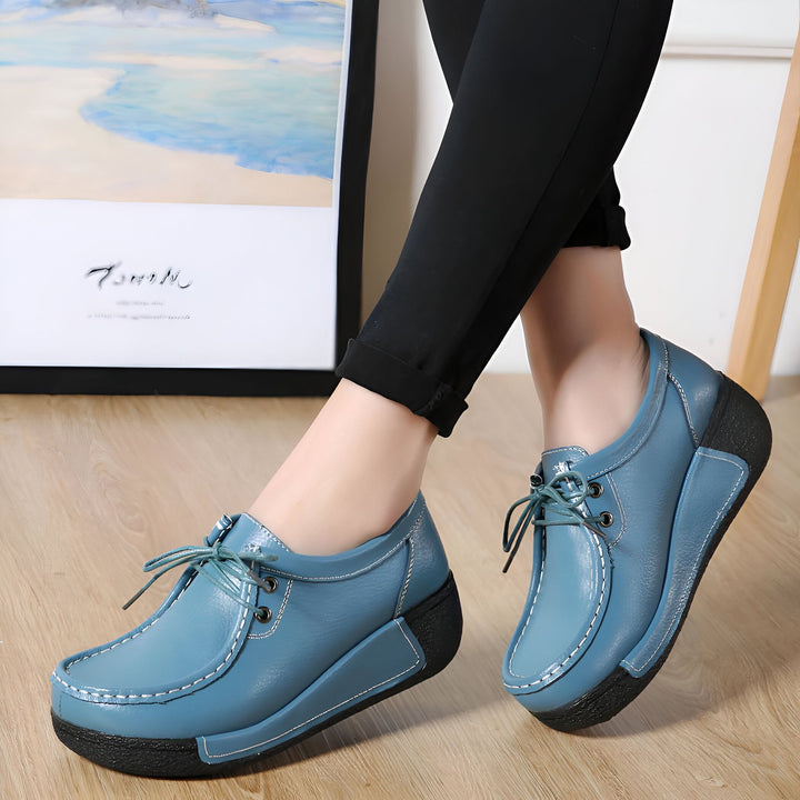 Gros plan de chaussures basses en cuir bleu portées par une femme avec un pantalon noir. Les chaussures ont des lacets et une semelle épaisse noire. Arrière-plan flou avec un tableau et une échelle., 45286815301813,45286815334581,45286815367349,45286815400117,45286815432885,45286815465653,45286815498421,45286815531189,45286815563957,45286815596725,45286815629493,45286815662261,45286815695029,45286815727797,45286815760565,45286815793333,45286815826101,45286815858869,45286815891637,45286815924405,452868