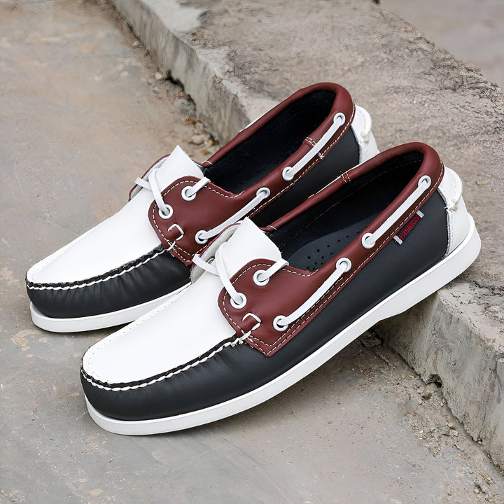 Deux chaussures bateau en cuir noir, blanc et bordeaux, avec des lacets blancs, posées sur une surface en béton. Chaussures décontractées, style nautique., 45287040745653,45287040778421,45287040811189,45287040843957,45287040876725,45287040909493,45287040942261,45287040975029