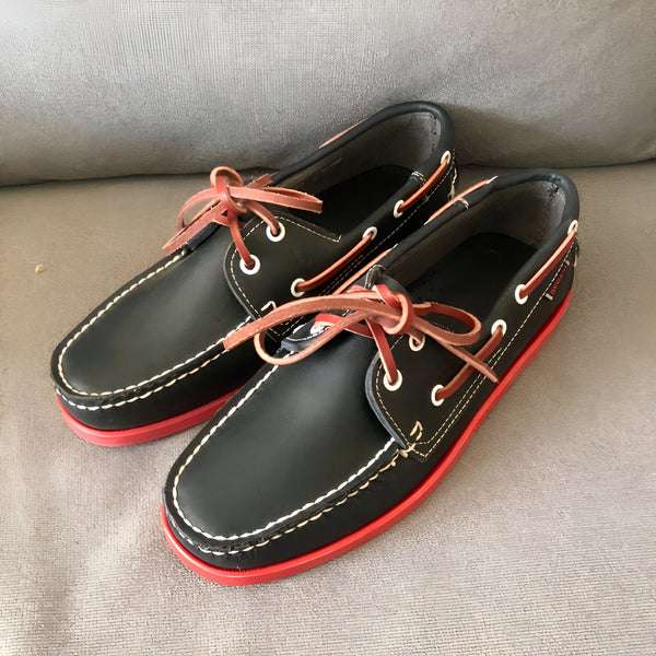 Chaussures bateau en cuir noir avec semelles rouges et lacets en cuir marron, posées sur un canapé gris. Style classique et élégant, parfait pour un look décontracté chic., 45286756843701,45286756876469,45286756909237,45286756942005,45286756974773,45286757007541,45286757040309,45286757073077,45286757105845,45286757138613,45286757171381,45286757204149,45286757236917,45286757269685,45286757302453,45286757335221,45286757367989,45286757400757,45286757433525,45286757466293,45286757499061,45286757531829
