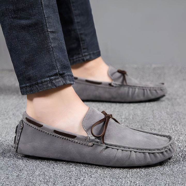 Gros plan de mocassins gris en daim portés avec un jean bleu foncé. Chaussures bateau décontractées avec détail de nœud en cuir marron. Mode masculine., 45286749995189,45286750027957,45286750060725,45286750093493,45286750126261,45286750159029,45286750191797,45286750224565,45286750257333,45286750290101,45286750322869,45286750355637,45286750388405,45286750421173,45286750453941,45286750486709,45286750519477,45286750552245,45286750585013,45286750617781,45286750650549,45286750683317,45286750716085,452867