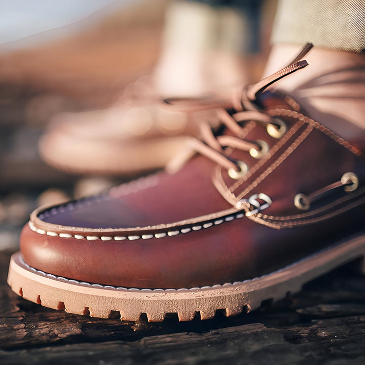 Gros plan d'une chaussure bateau en cuir marron sur une surface en bois. Détails de la couture blanche, des lacets et des œillets métalliques dorés. Style classique et élégant., 45287041466549,45287041499317,45287041532085,45287041564853,45287041597621,45287041630389,45287041663157,45287041695925,45287041728693,45287041761461
