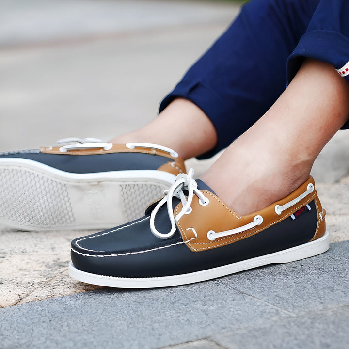 Gros plan sur des chaussures bateau Sebago en cuir bleu marine et marron clair portées avec un pantalon bleu marine. Les lacets sont blancs et la semelle est blanche et antidérapante. Style décontracté et élégant., 45287041990837,45287042023605,45287042056373,45287042089141,45287042121909,45287042154677,45287042187445,45287042220213,45287042252981,45287042285749,45287042318517,45287042351285,45287042384053,45287042416821,45287042449589,45287042482357,45287042515125,45287042547893,45287042580661,4528