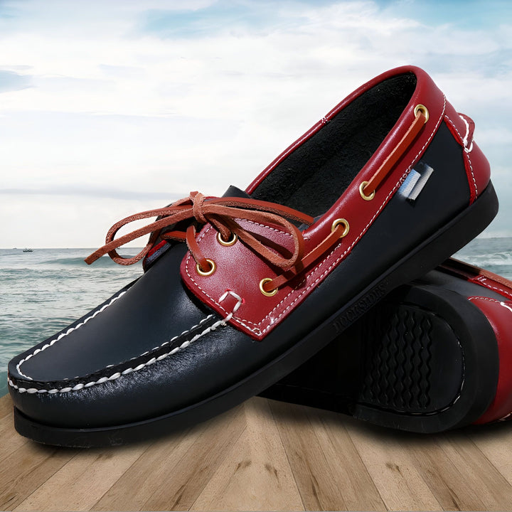 Chaussures bateau homme bicolores (bleu marine et rouge) avec lacets en cuir sur un fond marin flou. Détails cousus et œillets dorés. Élégance nautique et confort pour l'été., 45287025442997,45287025475765,45287025508533,45287025541301,45287025574069,45287025606837,45287025639605,45287025672373,45287025705141,45287025737909,45287025770677,45287025803445,45287025836213,45287025868981,45287025901749,45287025934517,45287025967285,45287026000053,45287026032821,45287026065589,45287026098357,452870261311