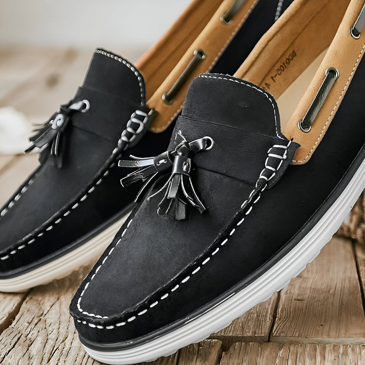 Deux mocassins noirs en daim avec des glands décoratifs, sur une surface en bois. Les chaussures ont des semelles blanches et des coutures contrastantes., 45287031046325,45287031079093,45287031111861,45287031144629,45287031177397,45287031210165,45287031242933,45287031275701,45287031308469,45287031341237,45287031374005,45287031406773,45287031439541,45287031472309,45287031505077,45287031537845,45287031570613,45287031603381,45287031636149,45287031668917,45287031701685,45287031734453,45287031767221,452870317