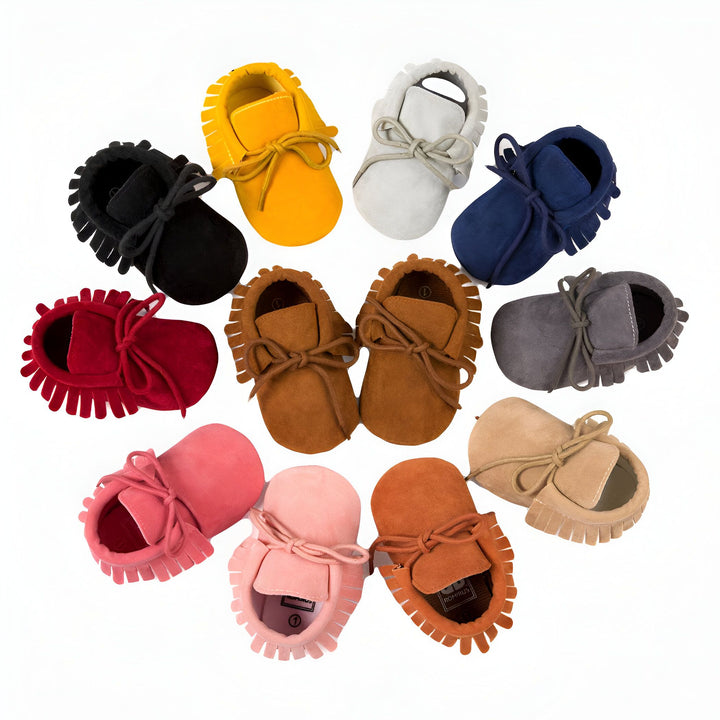 Chaussons mocassins pour bébé de différentes couleurs (jaune, gris, bleu marine, rouge, marron, rose, beige et noir) disposés en cercle sur fond blanc. Chaussures en cuir souple avec franges et lacets. Confort et style pour les premiers pas de bébé., 45286838894773,45286838927541,45286838960309,45286838993077,45286839025845,45286839058613,45286839091381,45286839124149,45286839156917,45286839189685,45286839222453,45286839255221,45286839287989,45286839320757,45286839353525,45286839386293,4528683941906