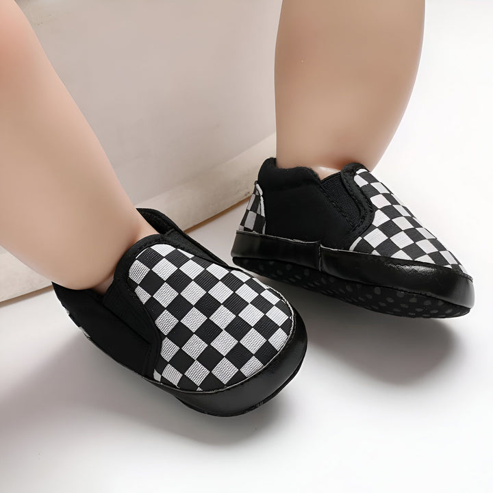 Gros plan sur des pieds de bébé chaussés de mocassins à damier noir et blanc. Chaussures souples pour bébé, confort et style. Idéal pour les premiers pas., 45286994116789,45286994149557,45286994182325,45286994215093,45286994247861,45286994280629,45286994313397,45286994346165,45286994378933,45286994411701,45286994444469,45286994477237,45286994510005,45286994542773,45286994575541,45286994608309,45286994641077,45286994673845