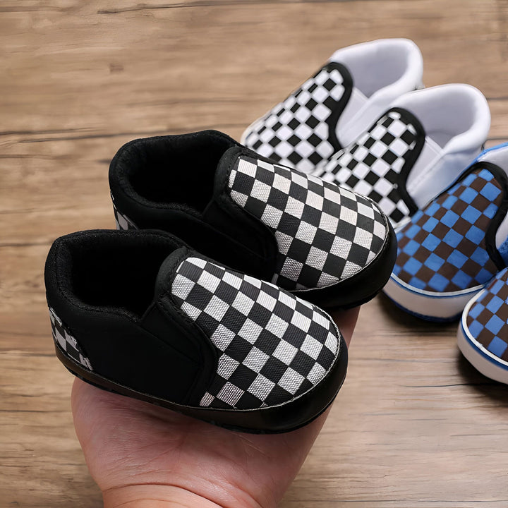 Gros plan de chaussons pour bébé à carreaux noirs et blancs dans la main d'un adulte. Des chaussures similaires à carreaux sont disposées à l'arrière-plan., 45286994116789,45286994149557,45286994182325,45286994215093,45286994247861,45286994280629,45286994313397,45286994346165,45286994378933,45286994411701,45286994444469,45286994477237,45286994510005,45286994542773,45286994575541,45286994608309,45286994641077,45286994673845