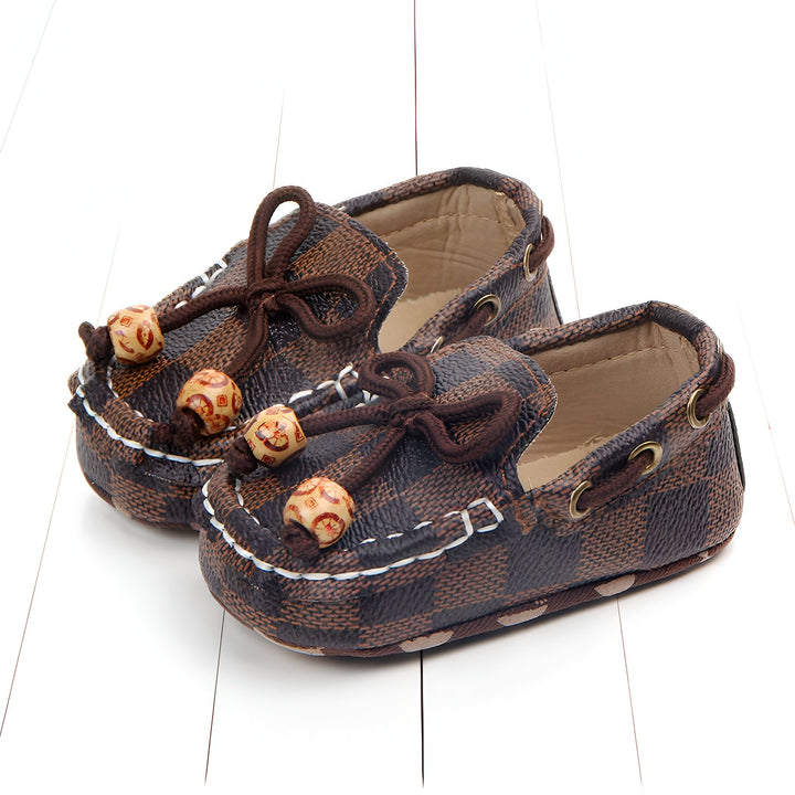 Paire de chaussures pour bébé en faux cuir marron à motif damier. Elles ont des lacets décoratifs avec des perles en bois. Chaussures de nouveau-né élégantes et confortables., 45286845939893,45286845972661,45286846005429,45286846038197,45286846070965,45286846103733,45286846136501,45286846169269,45286846202037