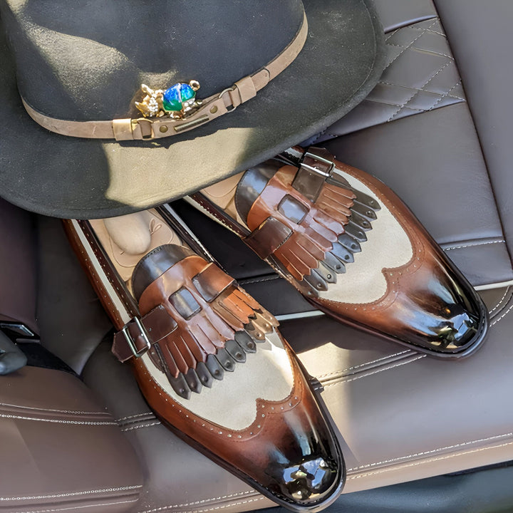 Nature morte élégante sur cuir : chapeau noir orné d'une broche fantaisie, et paire de mocassins en cuir marron et beige avec détails à franges. Mise en scène raffinée., 45286995460277,45286995493045,45286995525813,45286995558581,45286995591349,45286995624117,45286995656885,45286995689653,45286995722421,45286995755189,45286995787957,45286995820725,45286995853493,45286995886261,45286995919029,45286995951797,45286995984565,45286996017333