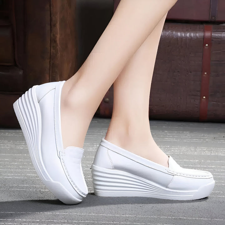 Gros plan sur des mocassins compensés blancs portés par une femme, devant un fond neutre. Chaussures décontractées et élégantes, idéales pour le confort et le style., 45286969606325,45286969639093,45286969671861,45286969704629,45286969737397,45286969770165