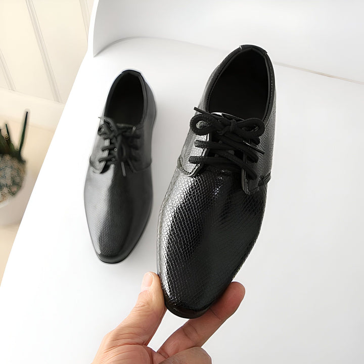 Chaussures habillées pour hommes en cuir noir avec texture serpent, lacets noirs. Une paire est posée sur un fond blanc, l'autre est tenue à la main., 45287021674677,45287021707445,45287021740213,45287021772981,45287021805749,45287021838517,45287021871285,45287021904053,45287021936821,45287021969589,45287022002357,45287022035125,45287022067893,45287022100661,45287022133429,45287022166197,45287022198965,45287022231733,45287022264501,45287022297269,45287022330037,45287022362805,45287022395573,45287022428