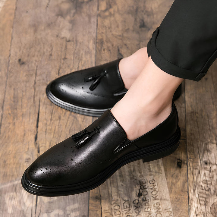 Gros plan sur des mocassins noirs en cuir portés par un homme avec un pantalon noir, posés sur un parquet en bois. Détail sur les glands décoratifs et le style élégant des chaussures., 45287087636661,45287087669429,45287087702197,45287087734965,45287087767733,45287087800501,45287087833269,45287087866037,45287087898805,45287087931573,45287087964341,45287087997109,45287088029877,45287088062645,45287088095413,45287088128181,45287088160949,45287088193717