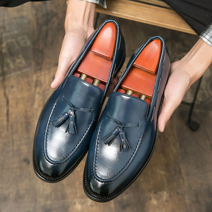 Deux mocassins bleus à glands en cuir sont tenus par les mains d'une personne. Des embauchoirs en bois sont insérés à l'intérieur des chaussures. Élégance et raffinement., 45286936805557,45286936838325,45286936871093,45286936903861,45286936936629,45286936969397,45286937002165,45286937034933,45286937067701,45286937100469,45286937133237,45286937166005,45286937198773,45286937231541,45286937264309,45286937297077,45286937329845,45286937362613,45286937395381,45286937428149,45286937460917,45286937493685,4