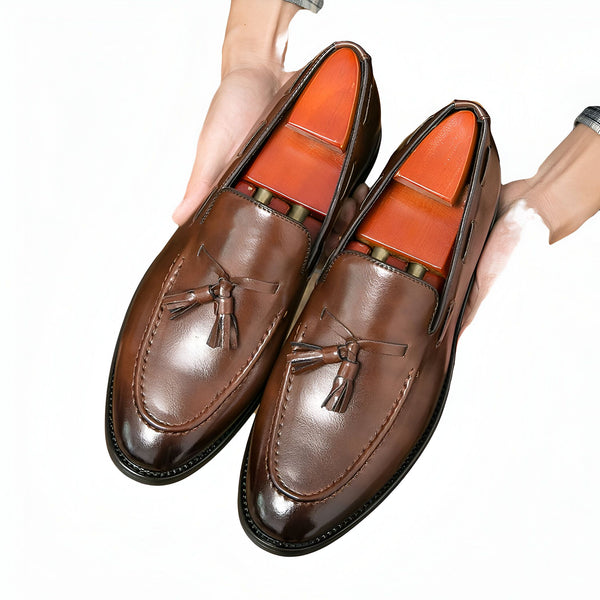 Deux mocassins en cuir marron avec glands et embauchoirs en bois, présentés par des mains sur un fond blanc. Chaussures élégantes pour hommes., 45286936805557,45286936838325,45286936871093,45286936903861,45286936936629,45286936969397,45286937002165,45286937034933,45286937067701,45286937100469,45286937133237,45286937166005,45286937198773,45286937231541,45286937264309,45286937297077,45286937329845,45286937362613,45286937395381,45286937428149,45286937460917,45286937493685,45286937526453,45286937559221,45