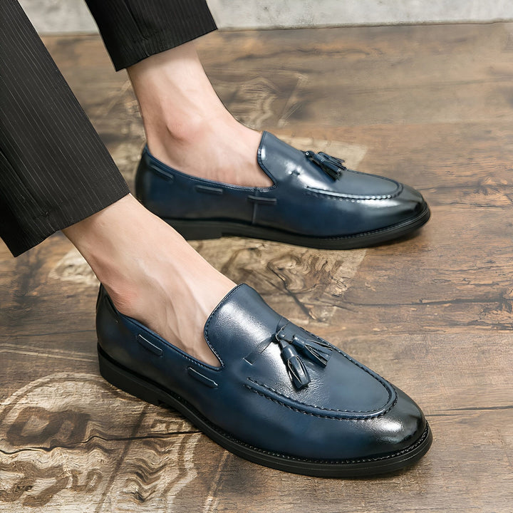 Gros plan de mocassins bleus en cuir avec glands portés par un homme en pantalon noir sur un plancher de bois., 45286936805557,45286936838325,45286936871093,45286936903861,45286936936629,45286936969397,45286937002165,45286937034933,45286937067701,45286937100469,45286937133237,45286937166005,45286937198773,45286937231541,45286937264309,45286937297077,45286937329845,45286937362613,45286937395381,45286937428149,45286937460917,45286937493685,45286937526453,45286937559221,45286937591989,45286937624757,4528693