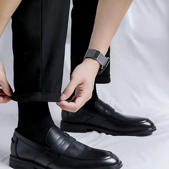 Gros plan d'un homme ajustant son pantalon noir avec des mocassins en cuir assortis. Sa montre argentée ajoute une touche moderne à ce style élégant et décontracté. Mode masculine, chaussures de ville., 45286715556021,45286715588789,45286715621557,45286715654325,45286715687093,45286715719861,45286715752629