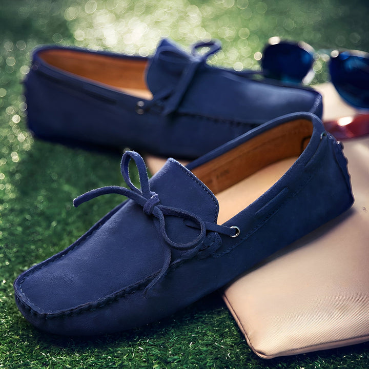 Mocassins bleus en daim avec lacets, reposant sur un coussin beige et de l'herbe. Des lunettes de soleil sont visibles en arrière-plan. Chaussures décontractées et élégantes., 45287105790133,45287105822901,45287105855669,45287105888437,45287105921205,45287105953973,45287105986741,45287106019509,45287106052277,45287106085045,45287106117813,45287106150581,45287106183349,45287106216117,45287106248885,45287106281653,45287106314421,45287106347189,45287106379957,45287106412725,45287106445493,45287106478261