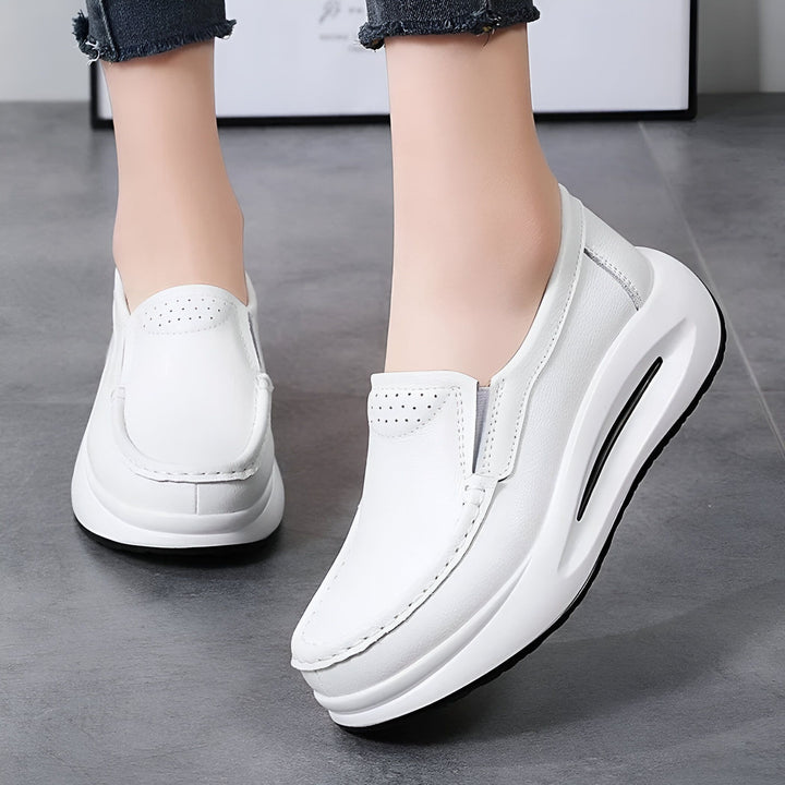 Gros plan de pieds portant des mocassins blancs en cuir à semelle épaisse. Chaussures décontractées et confortables pour femme., 45286645989557,45286646022325,45286646055093,45286646087861,45286646120629,45286646153397,45286646186165,45286646218933,45286646251701,45286646284469,45286646317237,45286646350005,45286646382773,45286646415541