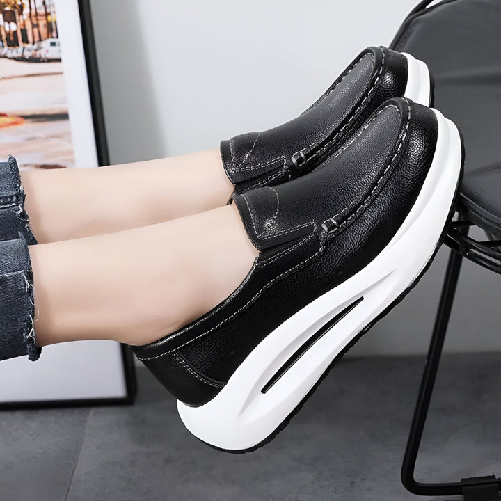 Mocassins noirs à semelle compensée blanche portés. Chaussures en cuir confortables et élégantes, idéales pour une tenue décontractée ou habillée. Détail de couture blanche., 45286645989557,45286646022325,45286646055093,45286646087861,45286646120629,45286646153397,45286646186165,45286646218933,45286646251701,45286646284469,45286646317237,45286646350005,45286646382773,45286646415541