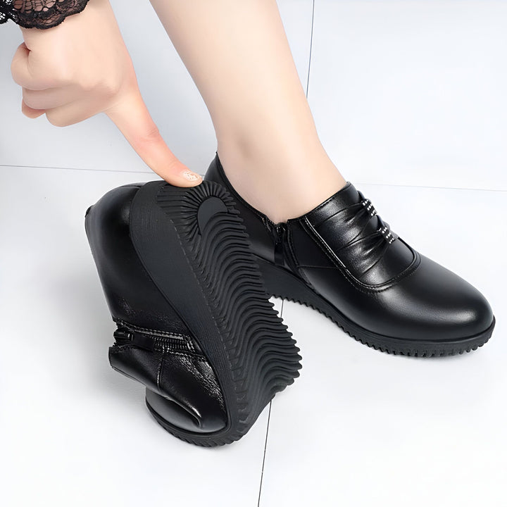 Chaussures noires confortables pour femmes avec semelle souple. Détail des chaussures de ville en cuir avec fermeture éclair latérale et petits strass décoratifs. Une main teste la flexibilité de la semelle., 45286793347253,45286793380021,45286793412789,45286793445557,45286793478325,45286793511093,45286793543861