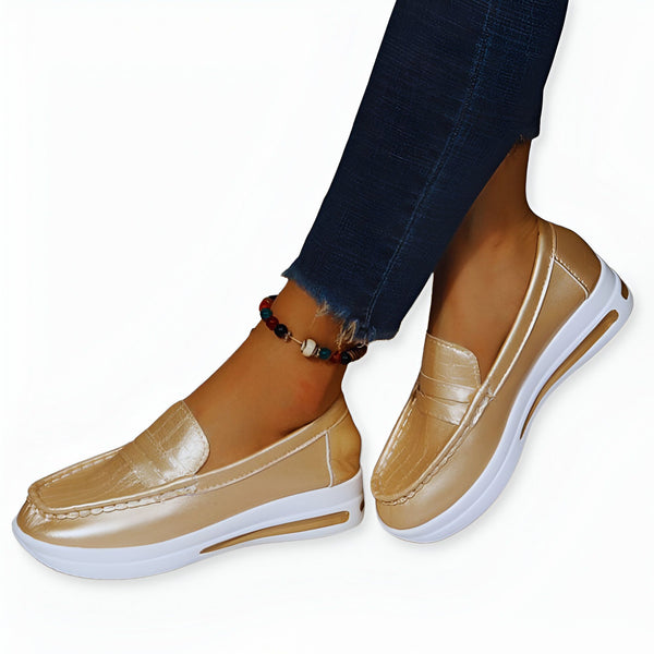 Gros plan sur des mocassins couleur or à semelle blanche portés avec un jean et une chaîne de cheville. Chaussures confortables pour femmes., 45286870778037,45286870810805,45286870843573,45286870876341,45286870909109,45286870941877,45286870974645,45286871007413,45286871040181,45286871072949,45286871105717,45286871138485,45286871171253,45286871204021,45286871236789,45286871269557,45286871302325,45286871335093,45286871367861,45286871400629,45286871433397,45286871466165,45286871498933,45286871531701,45286