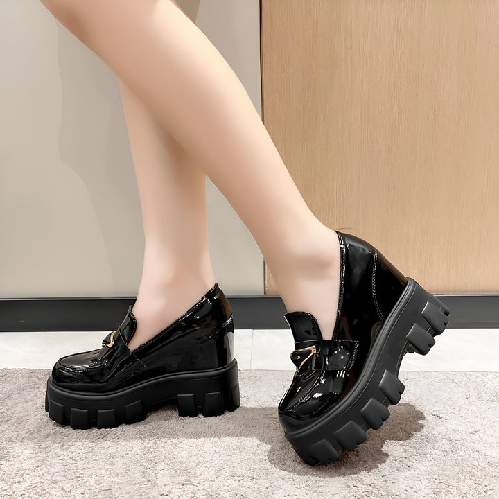 Gros plan de mocassins compensés noirs vernis, avec une boucle dorée sur le dessus. Chaussures tendance pour femme., 45286905938101,45286905970869,45286906003637,45286906036405,45286906069173,45286906101941,45286906134709,45286906167477,45286906200245,45286906233013,45286906265781,45286906298549