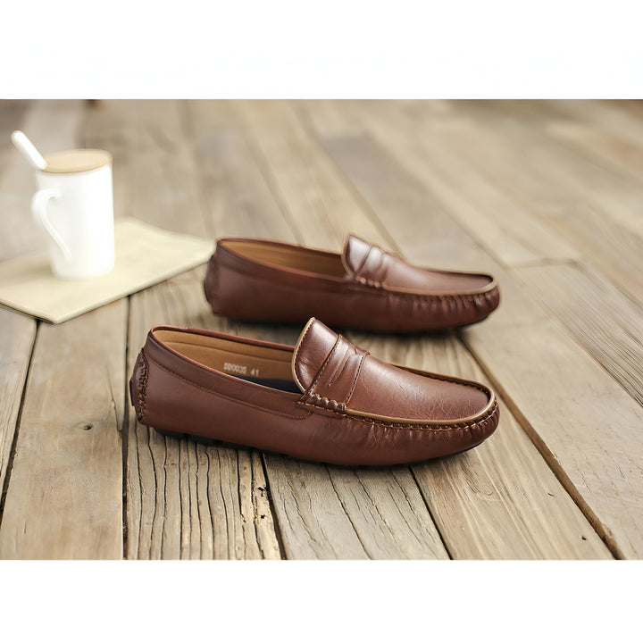 Mocassins en cuir marron pour hommes sur un plancher en bois. Chaussures décontractées avec des détails cousus. Tasse blanche à l'arrière-plan. Mode masculine., 45286873366709,45286873399477,45286873432245,45286873465013,45286873497781,45286873530549,45286873563317,45286873596085,45286873628853,45286873661621,45286873694389,45286873727157,45286873759925,45286873792693