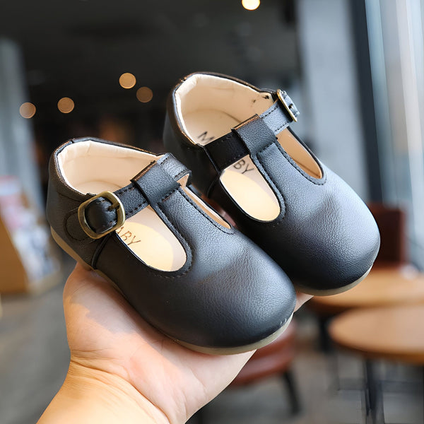 Gros plan sur une main tenant deux chaussures Mary Jane noires pour enfant, avec une bride à boucle dorée et la marque "BY" visible. Chaussures élégantes et confortables pour les petits., 45287038910645,45287038943413,45287038976181,45287039008949,45287039041717,45287039074485,45287039107253,45287039140021,45287039172789,45287039205557,45287039238325,45287039271093,45287039303861,45287039336629,45287039369397,45287039402165,45287039434933,45287039467701,45287039500469,45287039533237,45287039566005,452