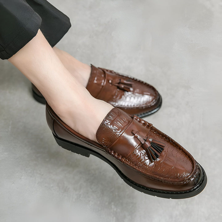 Vue rapprochée de mocassins marron en cuir avec des glands, style croco, portés par un homme avec un pantalon noir. Chaussures élégantes et classiques., 45287084949685,45287084982453,45287085015221,45287085047989,45287085080757,45287085113525,45287085146293,45287085179061,45287085211829,45287085244597,45287085277365,45287085310133,45287085342901,45287085375669,45287085408437,45287085441205