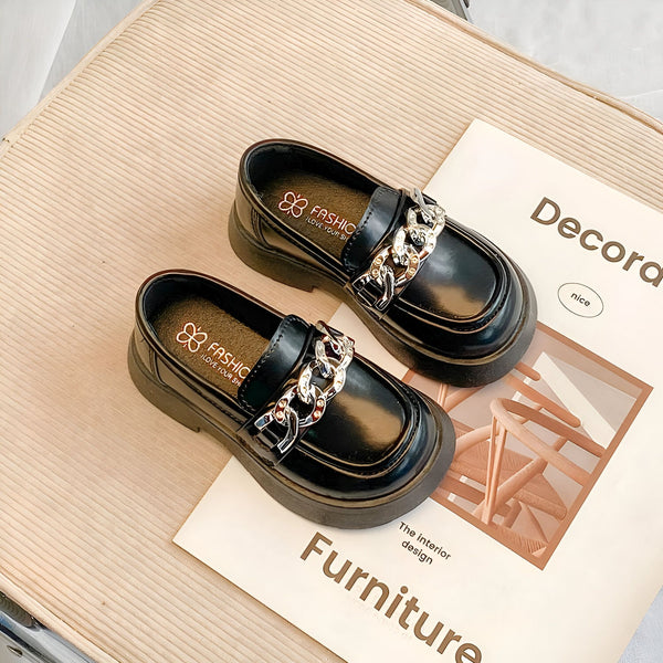 Deux mocassins noirs vernis avec chaînes argentées sur un magazine de décoration intérieure. Chaussures élégantes pour enfants, parfaites pour une tenue chic et tendance. Mode enfantine, accessoires de style., 45287036944565,45287036977333,45287037010101,45287037042869,45287037075637,45287037108405,45287037141173,45287037173941,45287037206709,45287037239477,45287037272245,45287037305013,45287037337781,45287037370549,45287037403317,45287037436085,45287037468853,45287037501621,45287037534389,452870375