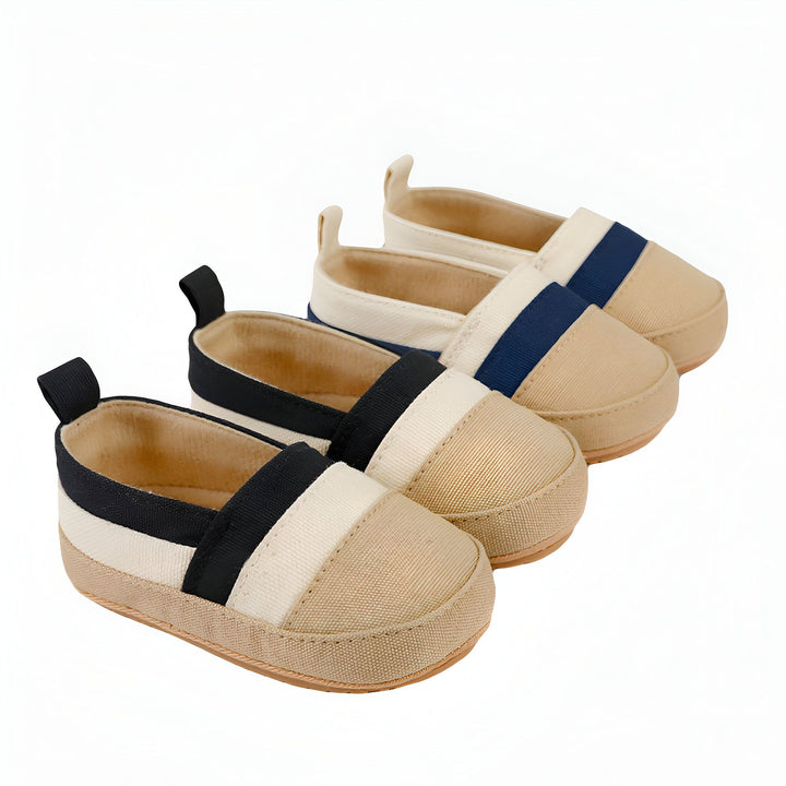 Trois paires de chaussures d'enfant en toile beige avec des bandes colorées (noir et blanc, bleu marine et blanc, blanc) disposées en rangée sur un fond blanc. Chaussures décontractées et confortables pour bébé., 45286820937909,45286820970677,45286821003445,45286821036213,45286821068981,45286821101749