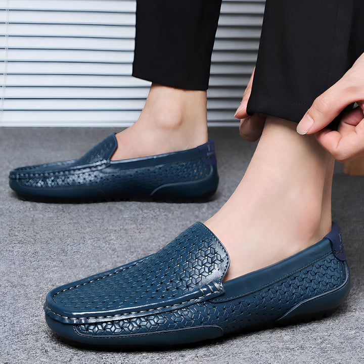 Homme portant des mocassins en cuir bleu marine à motifs perforés. Chaussures décontractées et élégantes. Détail du pantalon noir et des mains de l'homme., 45287138787509,45287138820277,45287138853045,45287138885813,45287138918581,45287138951349,45287138984117,45287139016885,45287139049653,45287139082421,45287139115189,45287139147957,45287139180725,45287139213493,45287139246261,45287139279029,45287139311797,45287139344565,45287139377333,45287139410101,45287139442869,45287139475637,45287139508405,45