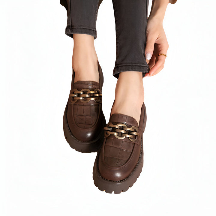 Vue rapprochée de chaussures mocassins marron en cuir avec détail chaîne dorée, portées par une femme en jean noir. Chaussures tendance et élégantes., 45286863470773,45286863503541,45286863536309,45286863569077,45286863601845,45286863634613,45286863667381,45286863700149,45286863732917,45286863765685,45286863798453,45286863831221