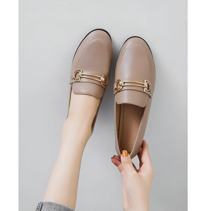 Mocassins en cuir beige avec ornement métallique doré, tenus par des mains, vue de dessus. Chaussures élégantes et confortables., 45286712311989,45286712344757,45286712377525,45286712410293,45286712443061,45286712475829,45286712508597,45286712541365,45286712574133,45286712606901,45286712639669,45286712672437,45286712705205,45286712737973,45286712770741,45286712803509,45286712836277,45286712869045,45286712901813,45286712934581,45286712967349,45286713000117,45286713032885,45286713065653,45286713098421,4