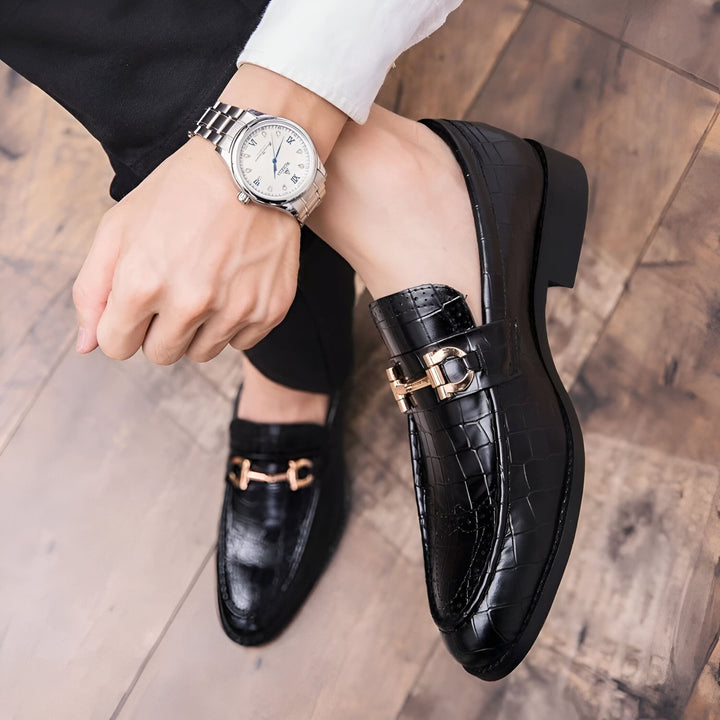 Gros plan sur des mocassins noirs en cuir texturé portés par un homme. On aperçoit également une montre élégante à son poignet. Chaussures de luxe avec détails dorés., 45286694322357,45286694355125,45286694387893,45286694420661,45286694453429,45286694486197,45286694518965,45286694551733,45286694584501,45286694617269,45286694650037,45286694682805,45286694715573,45286694748341,45286694781109,45286694813877,45286694846645,45286694879413,45286694912181,45286694944949